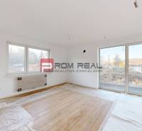 A room with a wooden floor and large windows provides brightness in the 2-room apartment.