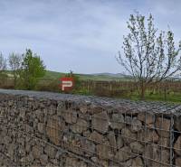 Gabion wall in Pezinok with vineyards and hills in the background.