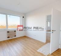 A bright room in a 2-room apartment with wooden flooring and a large window.