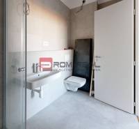 Bathroom with a shower, wall-hung toilet, and sink in a 2-room apartment.