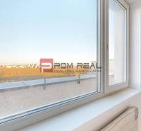 A room in a 2-room apartment with a view of the surroundings through a large window.