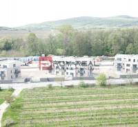 A new building on Limbašská Road in Pezinok, with vineyards and forests in the background.