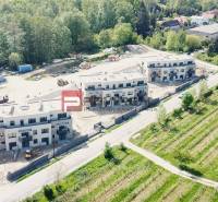 New buildings on Limbašská Road in Pezinok surrounded by greenery and unfinished spaces.