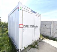 A white container on Šúrska Street in Modra, surrounded by greenery, warehouses, and halls.