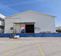Warehouse and hall buildings on Šúrska Street in Modra with parking spaces in the foreground.