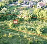 A plot for residential use on Poľná Street in Budmerice, surrounded by greenery and neighboring houses.