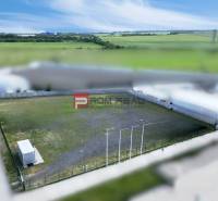 Production premises in Pezinok with a fenced outdoor area and a container, surrounded by fields.