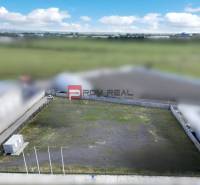 Production premises in Pezinok with an empty fenced plot and a container building.