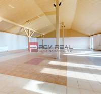 A spacious interior of a building with a patterned floor and a wooden ceiling.