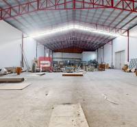 A spacious interior of a building with stored materials and an open ceiling with red beams.