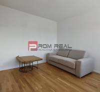 A room in a 4-room apartment with a sofa and a table on a wooden floor.