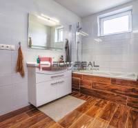A bathroom in a family house with a bathtub, a white sink, and a brown floor.