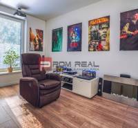 A game room with a comfortable armchair, wall decorations, a guitar, and an audio system in a family house.