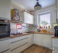 A kitchen in a family house with white cabinets, a wooden countertop, and appliances.