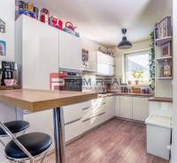 A kitchen in a family house with white furniture, a bar counter, and a coffee maker.