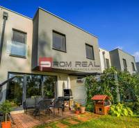 A family house in Slovenský Grob with a terrace, garden, garden furniture, plants under a blue sky.