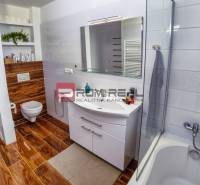 Bathroom in a family house with a bathtub, sink, and toilet, wooden floor.
