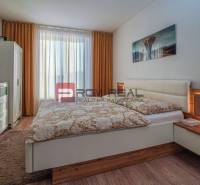 A bedroom in a family house with a bed, a wardrobe, and a TV on the wall.