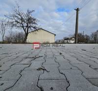 Pavement on Partizánska Street, next to warehouses and halls, with bare trees.