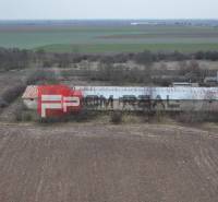 The building on Partizánska Street, surrounded by fields, warehouses, and halls in the background.