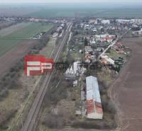 A railway track surrounded by fields and houses, on Partizánska Street, warehouses and halls are visible.