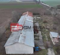 The image shows warehouses and halls on Partizánska Street, surrounded by fields and a railway.
