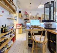 Interior of commercial premises with storage shelves, a wooden chair, and a counter with drinks.