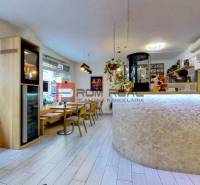 Café with chairs and tables, light wooden floor, decorations, and a bar counter.