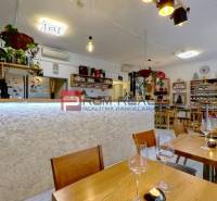 Interior of commercial spaces with wooden tables and a bar, decorative elements, and shelves.