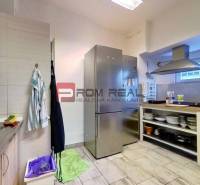 A kitchen in commercial premises with appliances, shelves, and tiles.