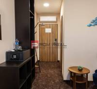 A hotel room with furniture, a safe, and a television, decorations on the wall.