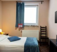 A room with a bed, a lamp, a television, and a window in an accommodation facility.