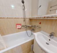 A bathroom in a 3-room apartment with a bathtub and a shower, tiled with beige tiles.