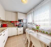 A kitchen in a 3-room apartment with flowers on the table and appliances.