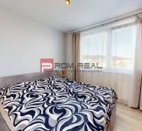 Bedroom in a 3-room apartment with a large window, bed, cabinet, and decorative throw.