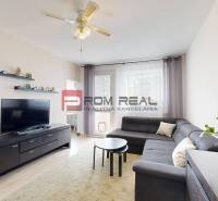 Living room of a 3-room apartment with a corner sofa and a TV stand, plants on the cabinet.