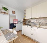 A kitchen in a 3-room apartment with a kitchenette, dining table, and flowers in a vase on the table.