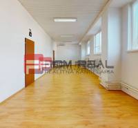 A spacious bright room with wooden flooring, radiators, and windows in warehouses and halls.