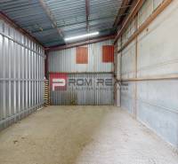 A metal storage room with open doors in an industrial hall.