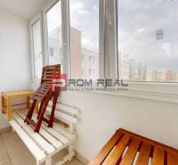 View from the balcony of a 4-room apartment with folding chairs and a table.