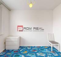 An empty room with a colorful carpet, a chair, and a dresser in a 4-room apartment.