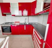 A red kitchen in a 4-room apartment with a gas stove and a white table.