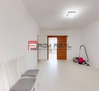 A bright room in a 4-room apartment with sliding doors and chairs. A vacuum cleaner set aside on the floor.