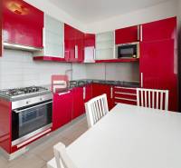 A kitchen with red cabinets and a gas stove in a 4-room apartment.