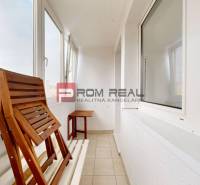 Glazed balcony of a 4-room apartment with wooden furniture and a view of the city.