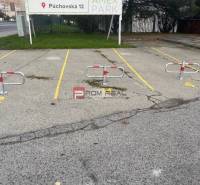 Parking spaces with blockers on Púchovská Street, Bratislava III in front of garages.