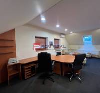 Office manufacturing space with chairs and a table, illuminated by artificial light.