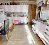A kitchen in a family house with white and pink cabinets, a dining table, and a stove.