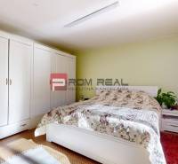 Bedroom with a large wardrobe, bed with a floral bedspread in a family house.