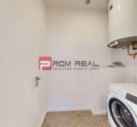 Laundry room in a family house with a washing machine and a boiler on the wall.